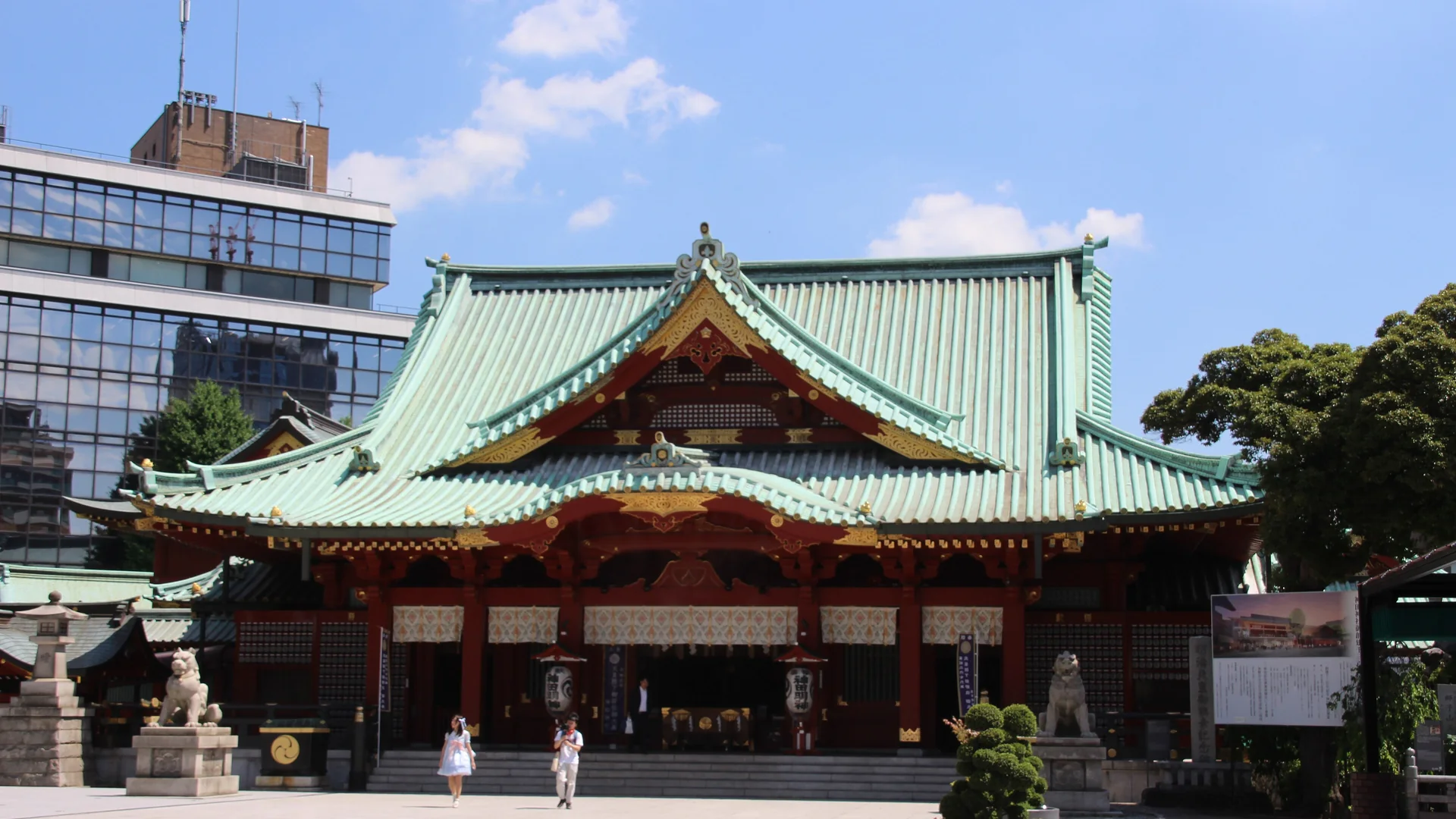 Kanda Myojin Tapınağı'nın yeşil kiremit çatılı vermilyon renkli ana salonu, açık bir taş avlunun karşısından, berrak bir günde görülüyor